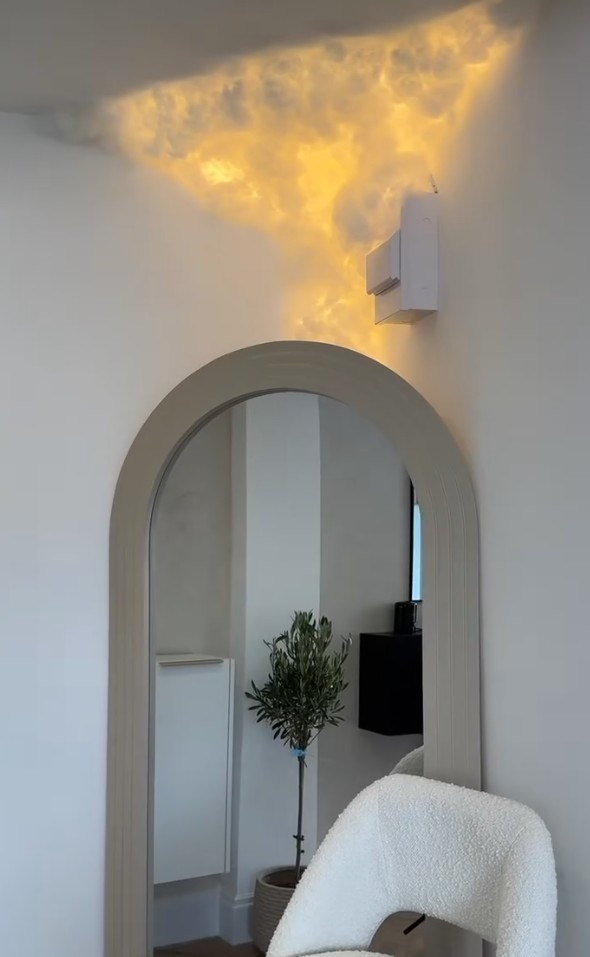 Backlit cloud installation glowing warm gold above an arched mirror in the clinic
