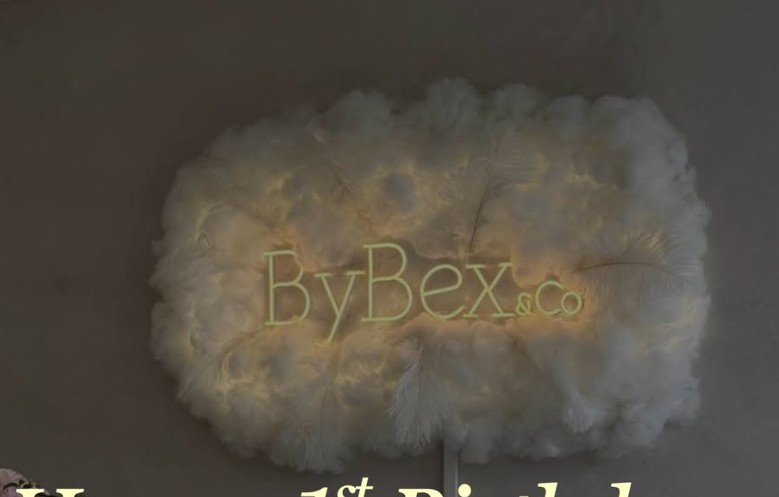 By Bex & Co illuminated feather cloud with glowing neon wordmark on the clinic wall